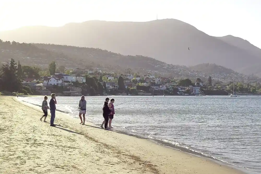 People on the beach at Sandy Bay with Mount Wellington behind